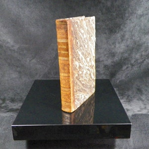 Puede incluir: Un libro encuadernado en cuero marrón con letras doradas en el lomo. El título del libro es "Le Livre Des Poesies".