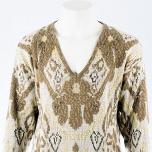 Könnte beinhalten: Ein V-Ausschnitt-Pullover mit einem braunen und cremefarbenen geometrischen Muster. Der Pullover hat lange Ärmel und gerippte Bündchen und Saum. Das Design zeigt Diamanten- und Blumenformen in Braun-, Creme- und Gelbtönen.