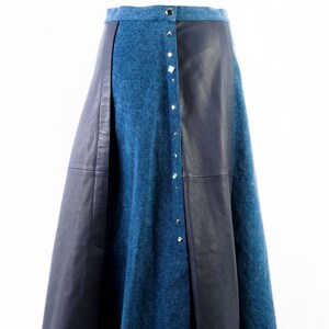 Könnte beinhalten: Ein Rock aus blauem Denim und schwarzem Leder mit Knopfverschluss und silbernen Verzierungen.