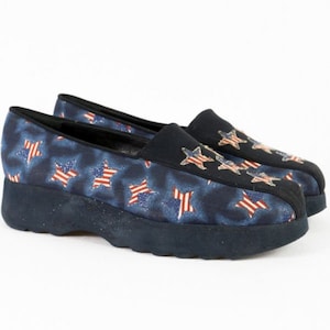 Könnte beinhalten: Ein Paar blaue Plateauschuhe mit einem rot-weiß-blauen Sternenmuster. Die Schuhe sind aus einem weichen, bequemen Material gefertigt und haben einen Slip-On-Stil.