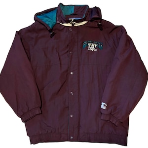 Op de afbeelding: Een bordeauxrode Starter-jas met capuchon en knoopsluiting. De capuchon heeft teal en donkergroene accenten. De jas heeft een logo op de borst en het Starter-logo op de mouw.