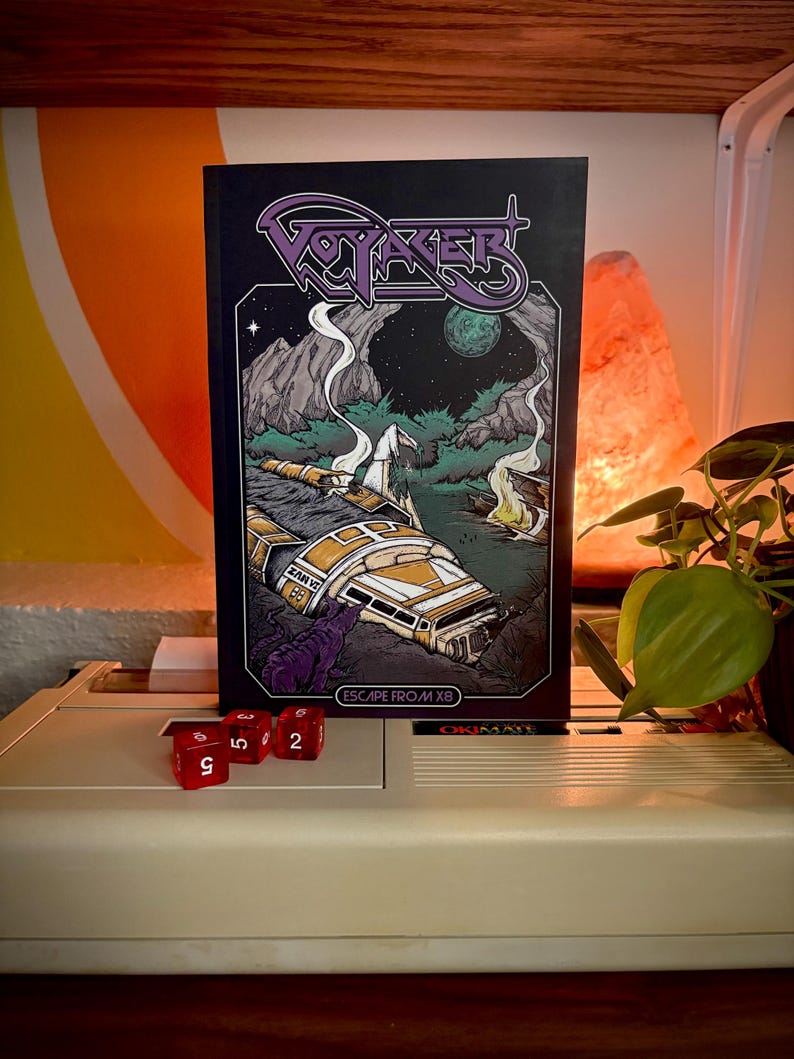 May include: A rectangular book titled Voyager Escape From X8 with a black cover featuring a purple logo and a detailed illustration of a crashed yellow and white spacecraft in a dark, rocky landscape with a green moon and a purple creature.