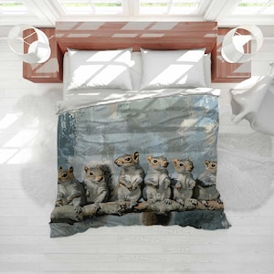 May include: A duvet cover featuring a watercolor illustration of six gray squirrels perched on a tree branch. The squirrels are depicted in a row, with varying poses and expressions. The background has a soft, blurred effect.