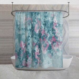 May include: A teal and pink floral shower curtain. The curtain features a distressed, painterly design with large pink flower blooms against a teal background. The curtain hangs from a curved metal rod above a white bathtub.