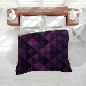 May include: A purple geometric patterned duvet cover with a repeating diamond design. The colour palette includes shades of deep purple, magenta, and violet. The bedding is on a bed with white pillows and a wooden headboard.