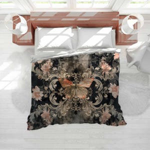 May include: A black and gray floral patterned comforter with a large butterfly design in the center. The butterfly has orange and tan wings. The comforter is on a bed with white pillows and a wooden headboard.