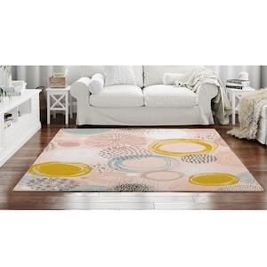May include: A pink and yellow abstract area rug with a pattern of circles and dots. The rug has a modern and contemporary design.