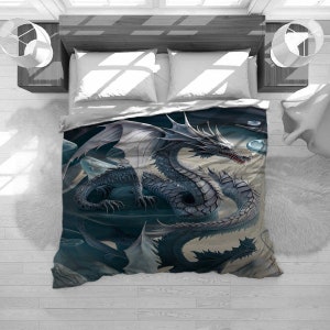 May include: A bedding set featuring a detailed illustration of a silver dragon with outstretched wings. The dragon is set against a dark, fantasy-themed background. The set includes a duvet cover and pillows, with a top-down view.