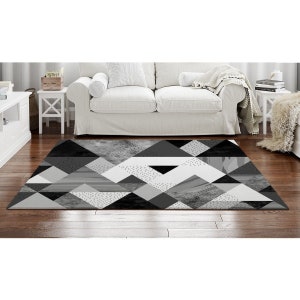 May include: Black and white geometric area rug with a pattern of triangles and dots. The rug is on a hardwood floor in a living room setting.