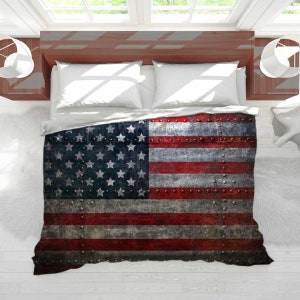 May include: A red, white, and blue American flag printed on a duvet cover. The flag is distressed and has a metallic texture with rivets.