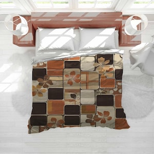 May include: A bed with a brown wooden frame, white pillows, and a patterned duvet cover. The duvet cover features a patchwork design with squares in shades of brown, tan, and cream, adorned with floral motifs. The room has white walls and a wooden floor.