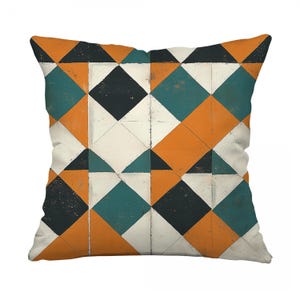 May include: Square cushion with a geometric design. The pattern is made up of repeating diamonds and triangles in orange, teal, black, and white. The cushion has a textured look and a neutral background.