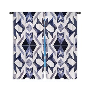 May include: A pair of window curtains with a geometric design in shades of blue and grey. The pattern features angular shapes and diamond motifs on a white backdrop. The curtains are suspended from a black curtain rod.