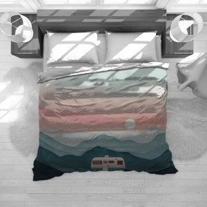 May include: A duvet cover with a mountain landscape design. The mountains are layered in shades of blue, green, and pink. A small camper van is parked in the foreground. The sun is setting behind the mountains.