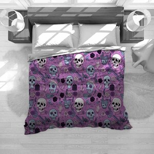 May include: A purple bedspread with a repeating pattern of skulls, roses, and other gothic-themed elements. The skulls are in various colors, including white, blue, and gray. The roses are in shades of purple and black. The bedspread is on a bed with white pillows and a gray comforter.
