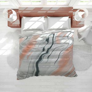 May include: A bed with a duvet cover featuring a marble design. The cover has a grey base with coral and black wavy lines. Two white pillows are visible, along with a wooden headboard and two bedside tables. The bed is in a bright room.
