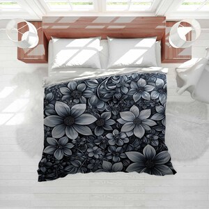 May include: A grayscale floral duvet cover with a detailed pattern of various sized flowers and leaves. The bedding is on a wooden bed frame with white pillows and a white rug.