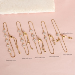 May include: Five gold chain bracelets with adjustable clasps. Each bracelet features a different number of crystal leaf charms, ranging from one to five leaves.