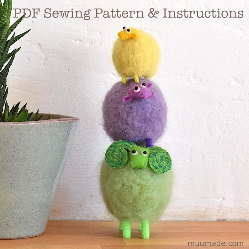 A happy fluffy sheep family: A set of 3 sewing patterns to make adorable sheep father, mother and baby! The yellow baby sheep is standing on top of its purple mother sheep, who is standing on top of the green father sheep.