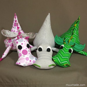 Three soft fabric plushies, all from the same set of sewing patterns: one T-rex dinosaur and two dragons. Their sewing patterns & instructions set is available for instant download from muumade.etsy.com.