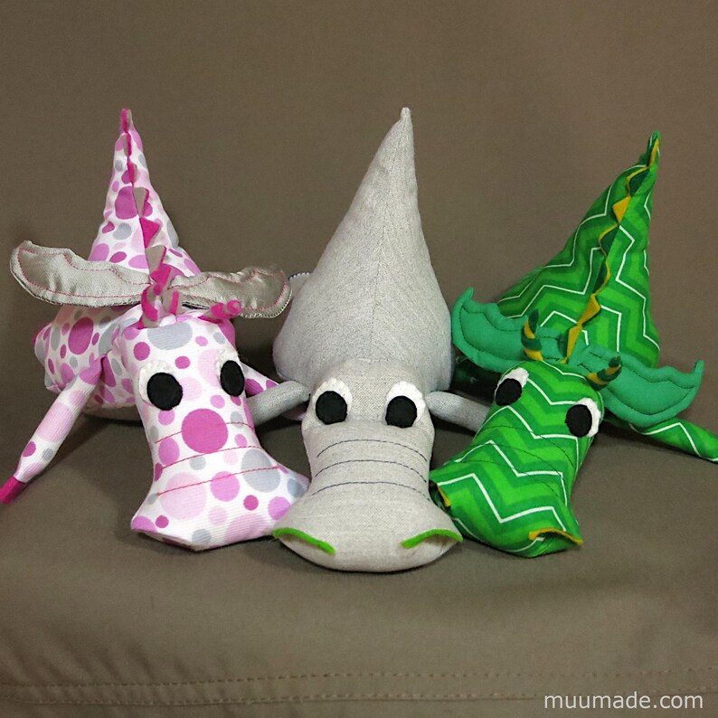 Three soft fabric plushies, all from the same set of sewing patterns: one T-rex dinosaur and two dragons. Their sewing patterns & instructions set is available for instant download from muumade.etsy.com.