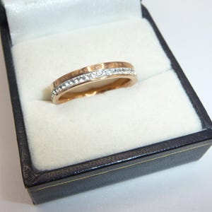 Symbolisk roséguldpläterad vigselring — Glittrande strasscirkel • Etsad "Vi ber för... framtiden" • Storlek Q i Storbritannien