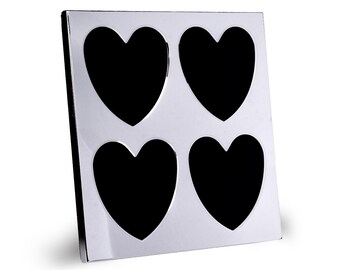 May include: A white picture frame with four black heart-shaped cutouts. The frame is made of a smooth, glossy material.