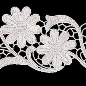 Może przedstawiać: Biała, haftowana, kwiatowa koronka z kwiatami przypominającymi stokrotki i misternymi ażurowymi detalami. Ozdoba ma płynny, zakrzywiony wzór, idealny do ozdabiania odzieży lub projektów rzemieślniczych. Delikatny, szczegółowy wzór jest na czarnym tle.