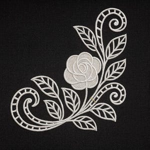 Può includere: Ricamo floreale bianco su sfondo nero. Il design presenta una rosa, foglie e volute decorative, creando un motivo delicato e dettagliato. Adatto a vari progetti di artigianato.