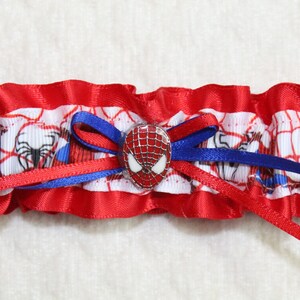 May include: Red and blue garter with a white spider-man design and a spider-man button.