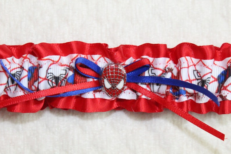 May include: Red and blue garter with a white spider-man design and a spider-man button.