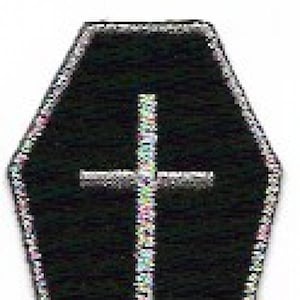 Puede incluir: Parche negro en forma de ataúd con borde plateado. Una cruz con un diseño iridiscente colorido está centrada en el parche. El parche es probablemente para ropa o accesorios.