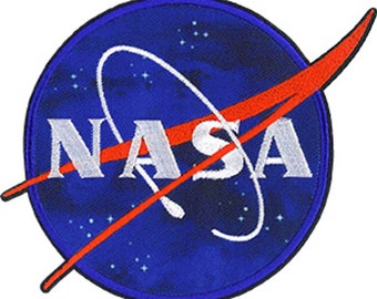 Può includere: Una toppa ricamata NASA blu e rossa con un logo in lettere stilizzate bianche e una linea curva rossa.