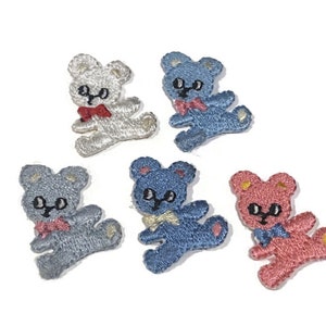 Op de afbeelding: Vijf geborduurde strijkpatches van teddyberen. De beren dragen strikjes en zijn in verschillende kleuren: wit, blauw en roze.