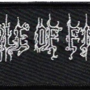 Op de afbeelding: Zwarte geborduurde patch met de witte tekst "CRADLE OF FILTH" in een gotisch lettertype.
