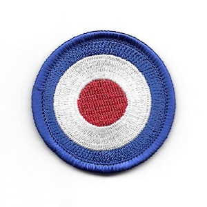 Könnte beinhalten: Ein gestickter Zielscheiben-Patch in Blau, Weiß und Rot. Die Mitte der Zielscheibe ist rot, umgeben von einem weißen Ring und dann einem blauen Ring.