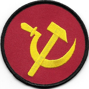 May include: A red and yellow embroidered patch with a hammer and sickle design. The patch is circular and has a black border.