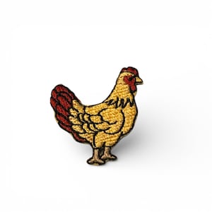 May include: Embroidered patch of a hen in profile. The hen has a yellow body with black detailing, a red comb and tail feathers, and brown feet. The patch is designed for clothing or accessories.