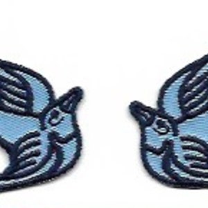 May include: Two blue embroidered swallow bird patches. The birds are facing opposite directions and have a traditional tattoo style.