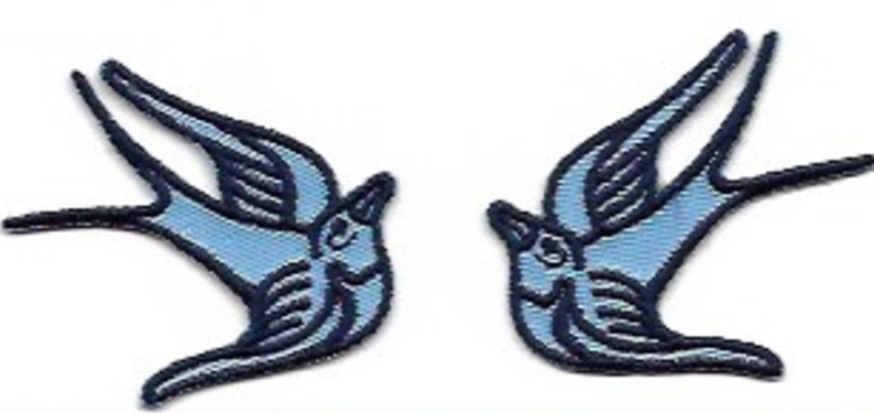May include: Two blue embroidered swallow bird patches. The birds are facing opposite directions and have a traditional tattoo style.