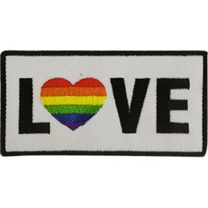 Op de afbeelding: Witte patch met een zwarte rand en het woord "LOVE" in zwarte letters. Een regenboog hart bevindt zich in het midden van de patch.