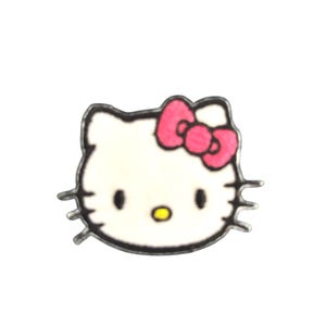 May include: A white, cartoon-style cat face with a pink bow and black eyes. The cat has a yellow nose and a black outline. The image is a close-up of a small, possibly decorative item.