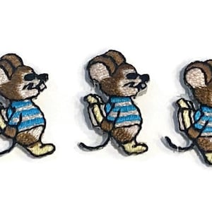 Op de afbeelding: Drie geborduurde patches van een cartoonmuis met een zonnebril en een blauw-wit gestreept shirt. De muis is bruin en beige met een zwarte staart en gele schoenen. De patches staan op een witte achtergrond.
