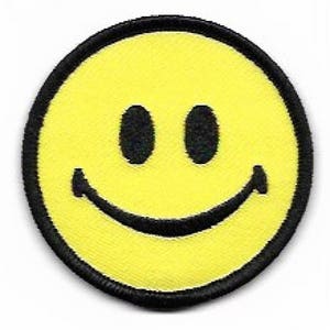 May include: A yellow smiley face with a black outline and two black eyes. The smiley face is on a black circular patch.