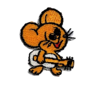 May include: An embroidered iron-on patch of a cartoon mouse wearing a diaper and holding a guitar. The mouse is yellow and has a red tongue sticking out.