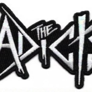 May include: Black and white embroidered patch with the text "The Adickes" in a stylised font.