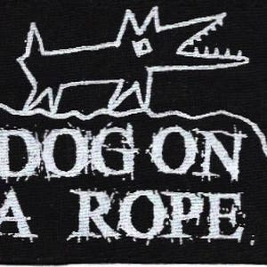 May include: Black and white embroidered patch with a simple line drawing of a dog on a rope. The text "DOG ON A ROPE" is below the dog.