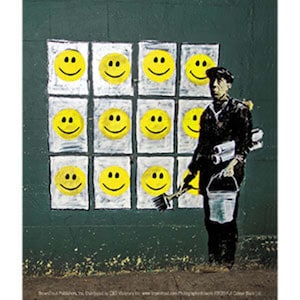Puede incluir: Arte callejero que representa una cuadrícula de caras sonrientes amarillas en una pared verde oscuro. Una figura vestida de negro, sosteniendo un pincel, un cubo y rollos de papel, parece estar pintando las caras.