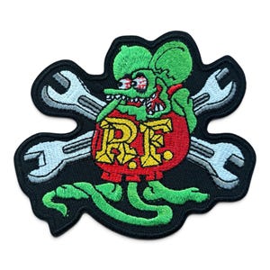 May include: An embroidered patch featuring a green cartoon rat with red eyes and a wide grin, positioned in front of two crossed silver wrenches. The rat holds a red circular emblem with the yellow letters R.F. printed in a bold, blocky font.