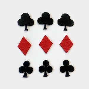 Può includere: Nove toppe in tessuto di feltro a forma di semi di carte da gioco. Tre toppe di trifoglio nere, tre toppe di quadri rosse e tre toppe di trifoglio nere.